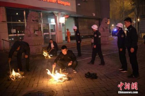 资料图：城管执法人员劝阻民众停止在街边焚烧纸钱。中新社记者