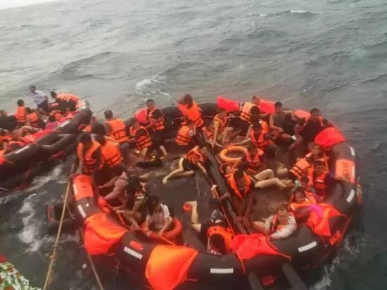 30余名生还者身着救生衣坐在圆形充气筏上，身后船上堆满绳索等工具。图片来自网络