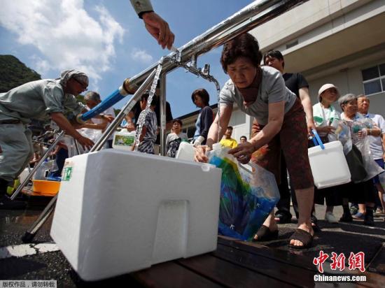当地时间7月9日，日本广岛三原居民在被洪水淹没地区附近一个紧急供水站接水。
