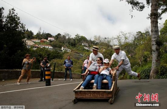 资料图片：游客在葡萄牙体验人力推动的竹篮雪橇，感受风驰电掣的下坡刺激。