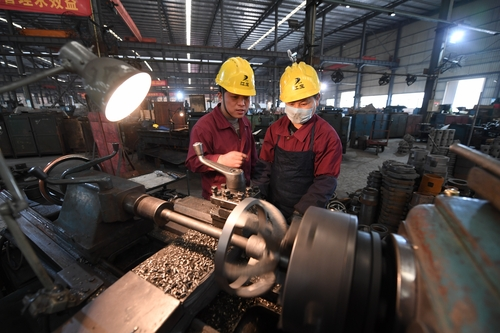 2019年2月25日，全国人大代表、江西气体压缩机有限公司车工组组长陈赣飞（左）正在与工友们钻研生产技术。（人民视觉）
