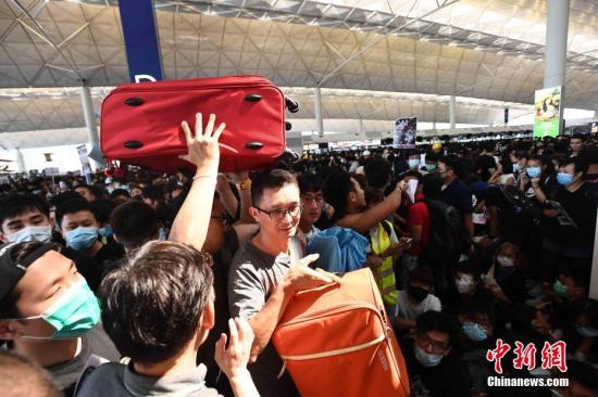 8月12日下午三时许，大批非法集结于香港国际机场的示威者拆走铁马，进入原先只限持机票旅客才可进入的离境大堂禁区前通道位置。受非法集结影响，大批登机旅客受阻，航班取消。中新社记者