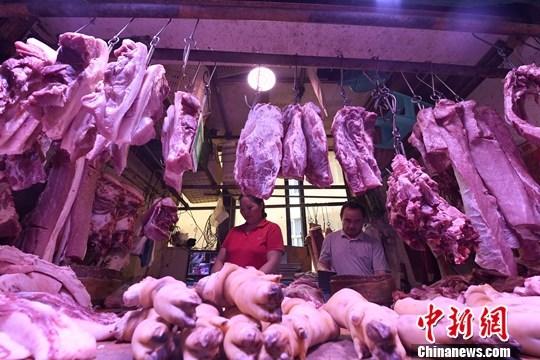 资料图：一家农贸市场内，商贩正在摆放猪肉。中新社记者