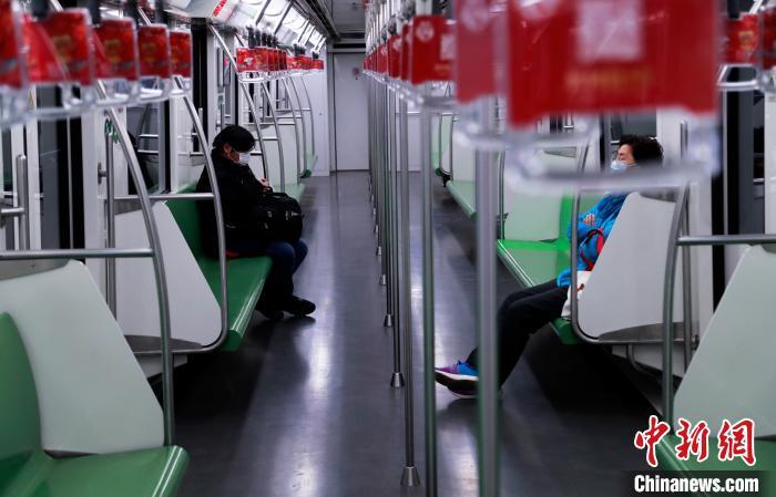 资料图：两位乘客戴着口罩在地铁上“隔位而坐”。