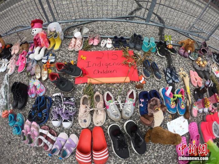 当地时间6月2日，在位于多伦多的加拿大安大略省省议会大楼门前，人们摆放了上百双童鞋和各式玩偶、鲜花、留言卡等，为该国一处原住民寄宿学校旧址发现215具儿童遗骸之事志哀。中新社记者
