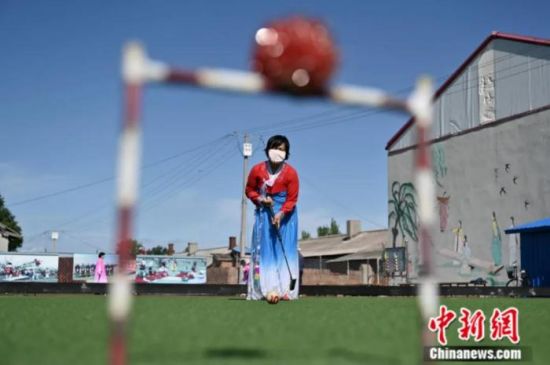 2020年6月，黑龙江省桦川县星火朝鲜族乡星火村，身着民族服饰的村民在门球场打门球。1951年，这里曾创办了新中国第一个集体农庄。如今，星火村已告别了手工插秧收割时代，从当年的合作生产转为现在的合作经营，实现了由传统农业向“科技农业”“订单农业”转变，走出了一条强村富民的新路子。中新社记者 张兴龙 摄
