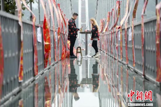 2019年1月,湖南长沙石燕湖玻璃桥上贴满了春联,两名外籍游客在玻璃桥上学习写春联。中新社记者 杨华峰 摄 2019年1月,湖南长沙石燕湖玻璃桥上贴满了春联,两名外籍游客在玻璃桥上学习写春联。中新社记者 杨华峰 摄