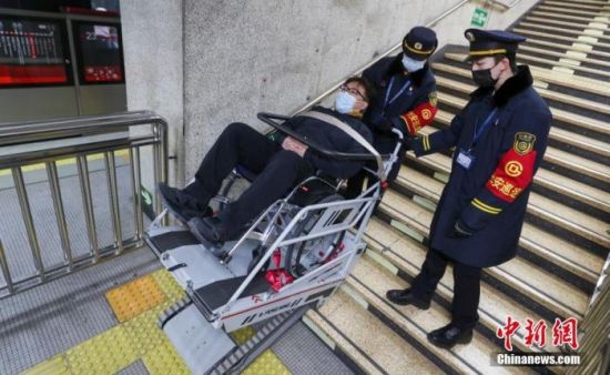资料图：北京地铁1号线五棵松站，一名使用轮椅的乘客在车站工作人员的协助下使用轮椅升降平台进站。 中新社记者 贾天勇 摄