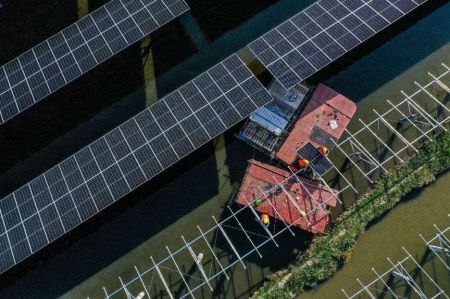 2022年3月7日，在安徽省铜陵市义安区西联镇110兆瓦“渔光互补”光伏发电项目施工现场，电力工人正在施工。陈晨/人民图片
