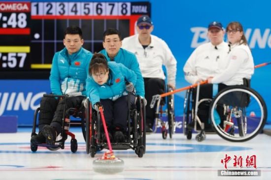 3月10日，北京2022年冬残奥会轮椅冰壶循环赛第十五轮比赛在国家游泳中心举行，中国队以6比3战胜英国队。图为中国队队员闫卓(蓝衣前排)掷壶。 中新社记者 韩海丹 摄
