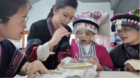 （全国人大代表、布依族服装技艺非遗传承人李利在指导绣娘）