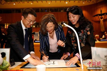 当地时间4月13日，以“翰墨和鸣，华章同赋”为主题的联合国中文日庆祝活动在纽约联合国总部举行。图为联合国副秘书长弗莱明(中)使用京师AI书法屏体验中文书法。中新社记者 廖攀 摄