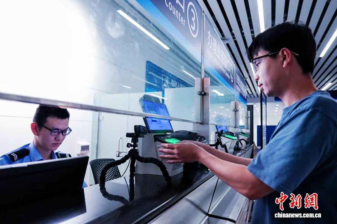 白云边检站移民管理警察为旅客办理快捷通道信息采集手续。白云边检站