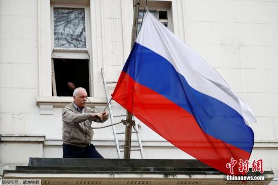 当地时间2018年3月14日，一名男子将俄罗斯驻英国大使馆门前的俄罗斯国旗取下。英国首相特蕾莎·梅此前宣布，将驱逐23名俄罗斯外交官。