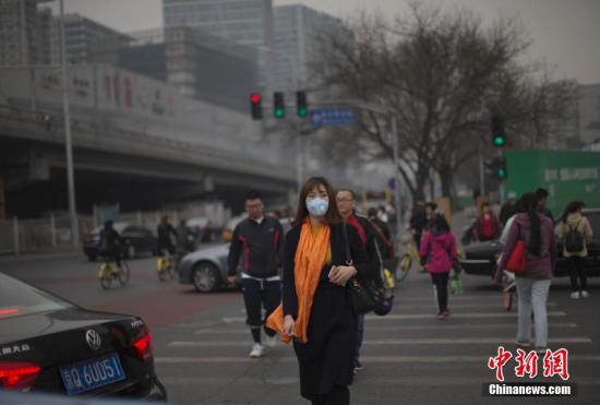 资料图：北京市民在雾霾中出行。