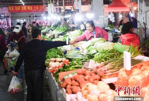 资料图：重庆一农贸市场内菜商正在忙碌卖菜。中新社记者