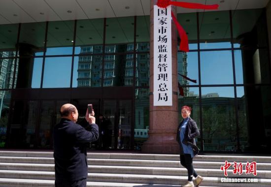 4月10日，新组建的国家市场监督管理总局在北京正式挂牌。图为民众与新牌合影。中新社记者
