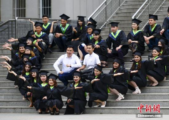 资料图：即将毕业的大学生身着学士服和老师在校园内拍摄毕业照。中新社记者