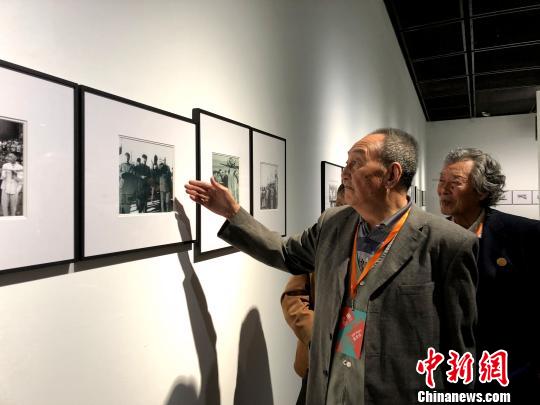 展览现场，照片提供者82岁的朱康洛正在讲述照片背后的故事。额丽其格