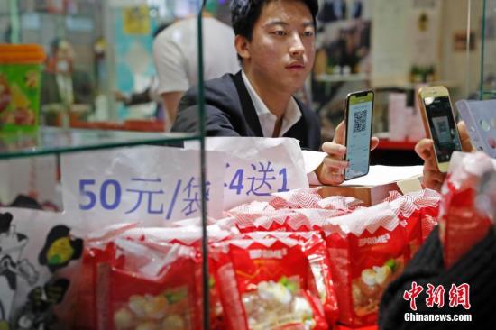 11月10日，首届中国国际进口博览会食品及农产品展区，参观者扫码支付购买商品。中新社记者