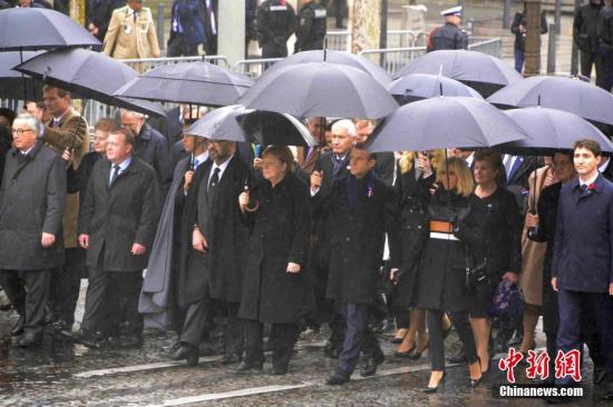 资料图：当地时间11月11日，纪念一战结束100周年官方仪式在巴黎举行。图为法国总统马克龙、德国总理默克尔、加拿大总理特鲁多、欧盟委员会主席容克等政要在雨中共同走向凯旋门的仪式现场。中新社记者