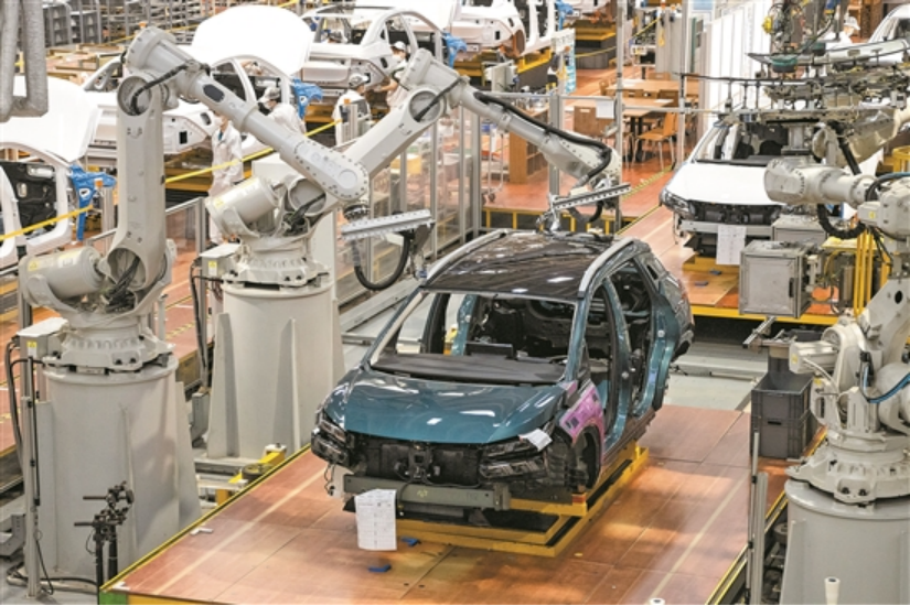 广汽埃安的智能生产车间内，机械臂进行车辆安装工作